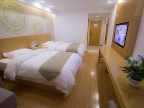 Habitación de hotel con dos camas, una recepción, un televisor y una planta.