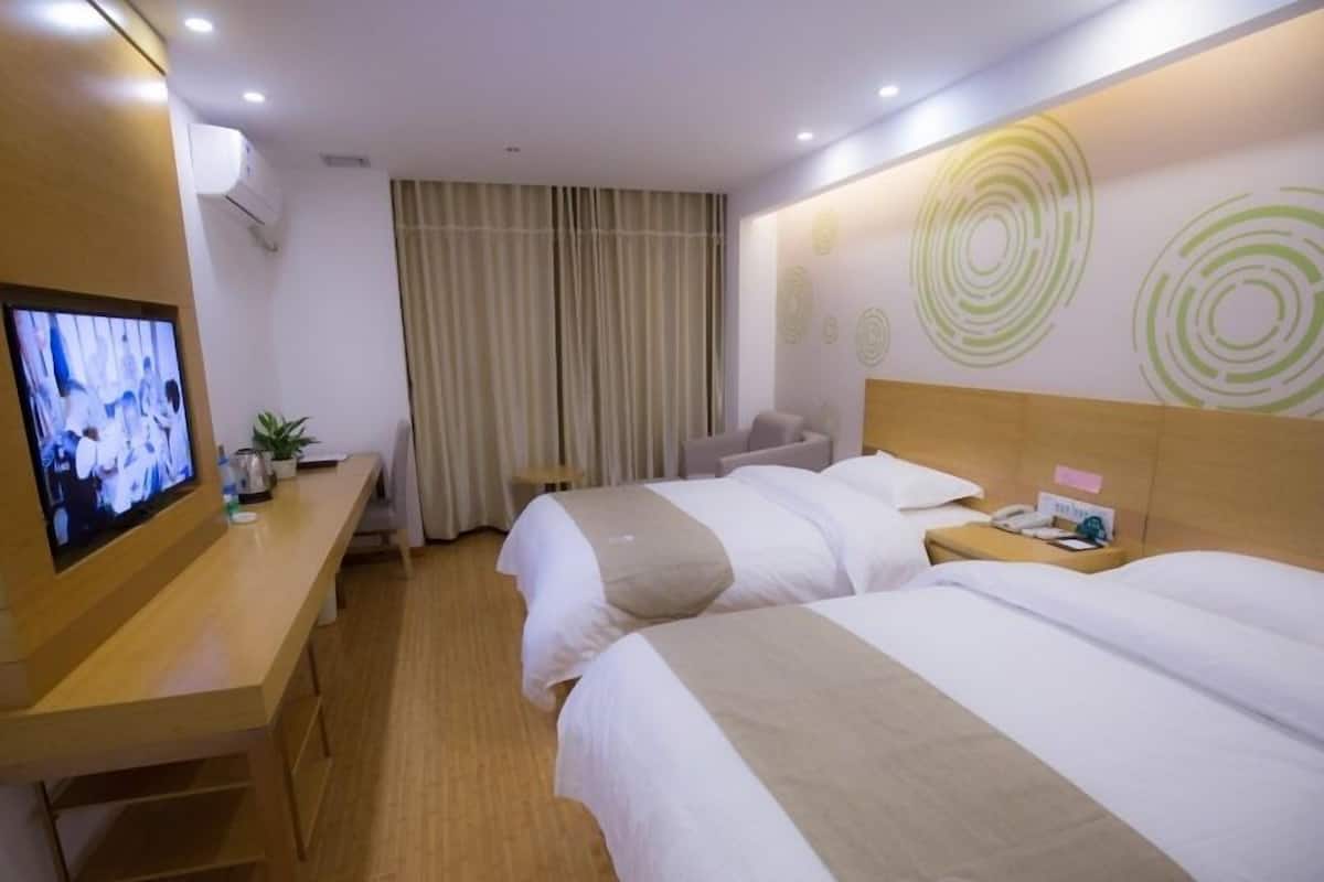 A hotel room with two beds, a TV on a wooden desk, a small table, and a chair.