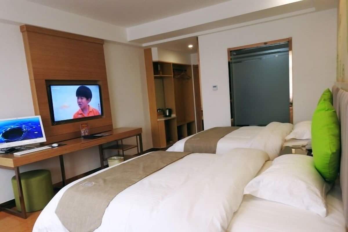 A hotel room with two beds, a desk with a computer, a television, and a wardrobe.