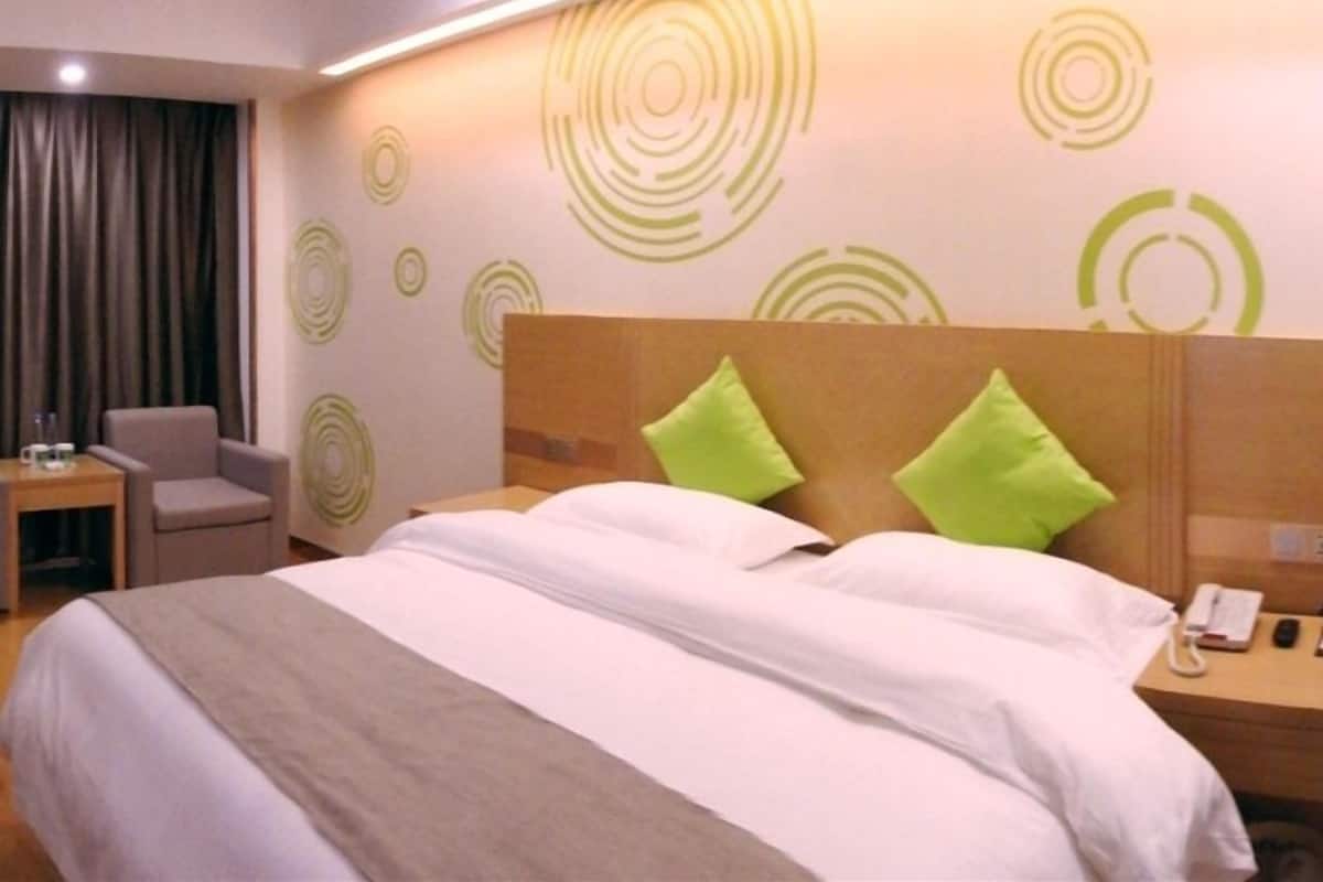 A hotel room with a bed, a nightstand, a chair, and a wall with circular patterns.