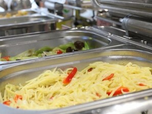 Buffet con diversas opciones de comida, incluyendo pasta con pimientos rojos.