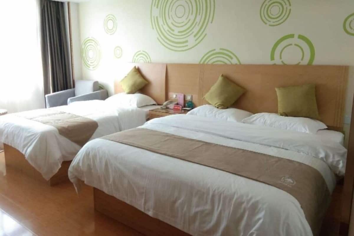 A hotel room with two beds, each with white linens and green circular wall art.