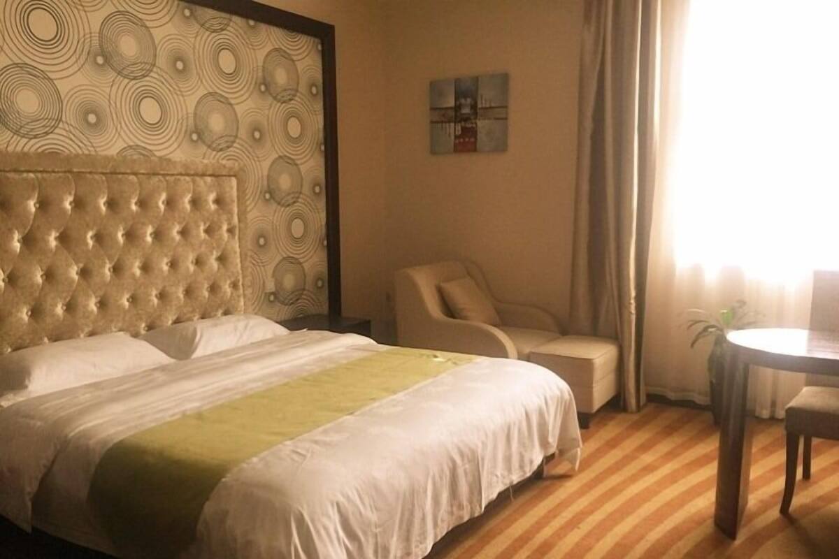 Une chambre d’hôtel avec un grand lit, une chaise, une petite table et un tableau au mur.
