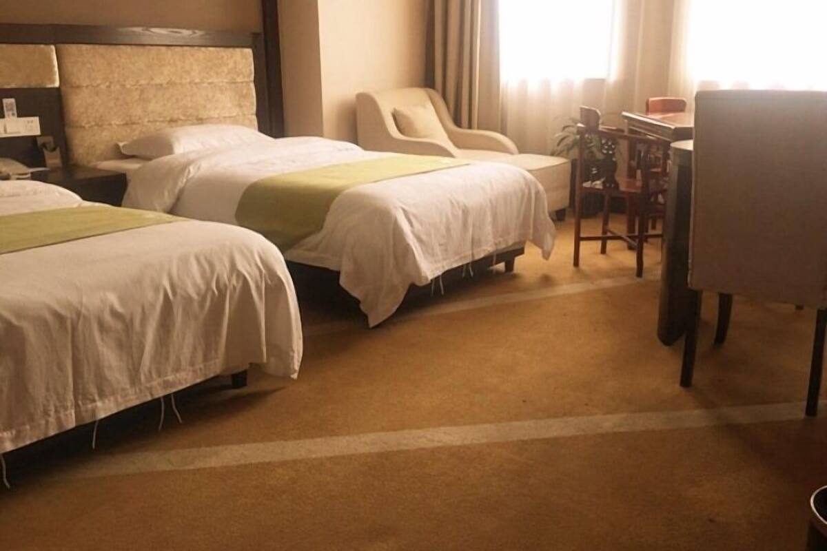 Une chambre d’hôtel avec deux lits, un bureau et une chaise.