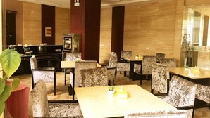 Een hotel lobby met een centrale zithoek, een receptiebalie en een grote spiegel aan de muur.
