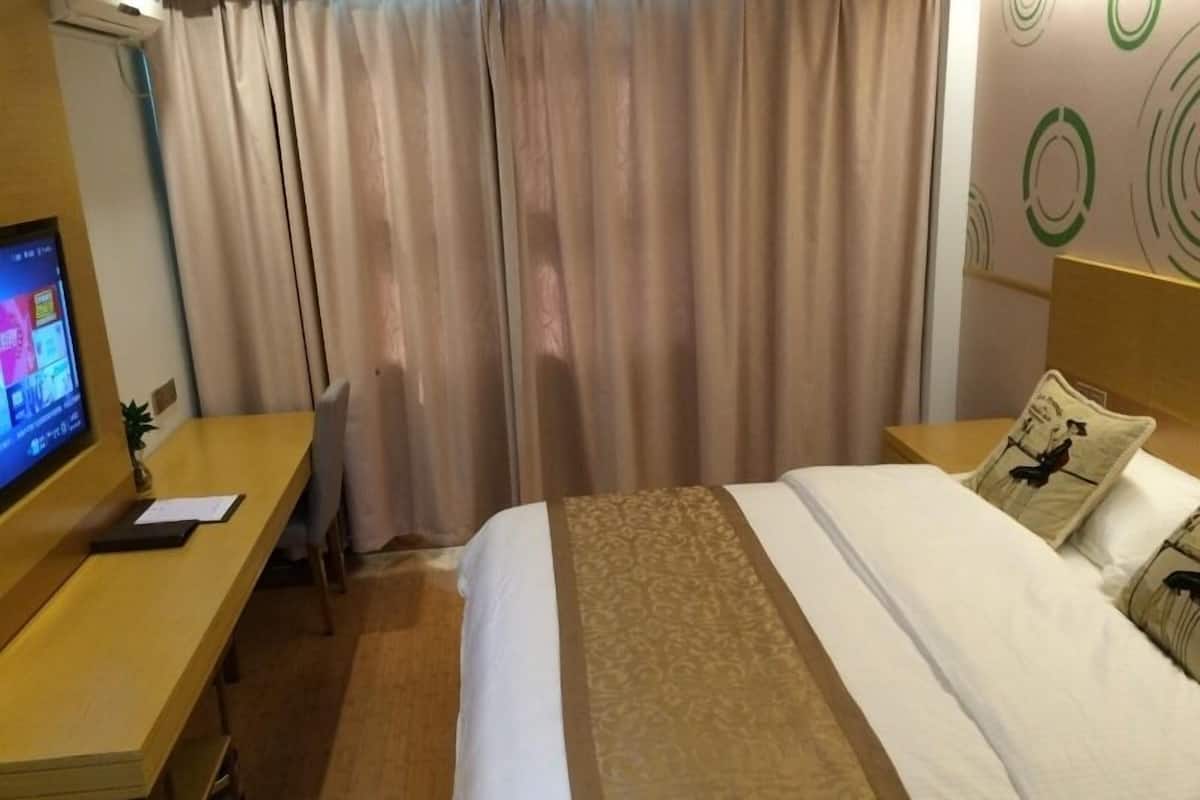 Hotellihuone, jossa on sänky, työpöytä ja televisio.