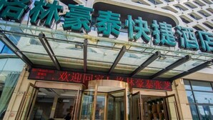 A hotel entrance with a modern glass facade and a sign indicating a promotion for a special rate. - GreenTree Inn Nantong Tongzhou Zhangzhishan Town Deli Square Express Hotel (Nantong)