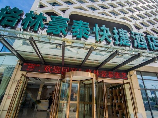 A hotel entrance with a modern glass facade and a sign indicating a promotion for a special rate.