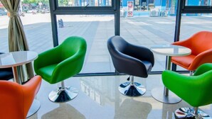 A modern interior with large windows, green and black chairs, and a reflective floor. - GreenTree Inn Nantong Tongzhou Zhangzhishan Town Deli Square Express Hotel (Nantong)