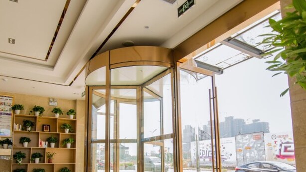 A hotel lobby with a revolving door, glass walls, and a view of the cityscape. - GreenTree Inn Nantong Tongzhou Zhangzhishan Town Deli Square Express Hotel (Nantong)