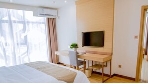 A modern hotel room with a large bed, a desk with a chair, a flat-screen TV, and an air conditioning unit. - GreenTree Inn Nantong Tongzhou Zhangzhishan Town Deli Square Express Hotel (Nantong)