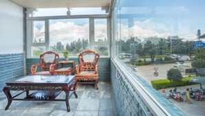 Ein Balkon mit Blick auf ein traditionelles Gebäude, einem Tisch und zwei verzierten Stühlen.