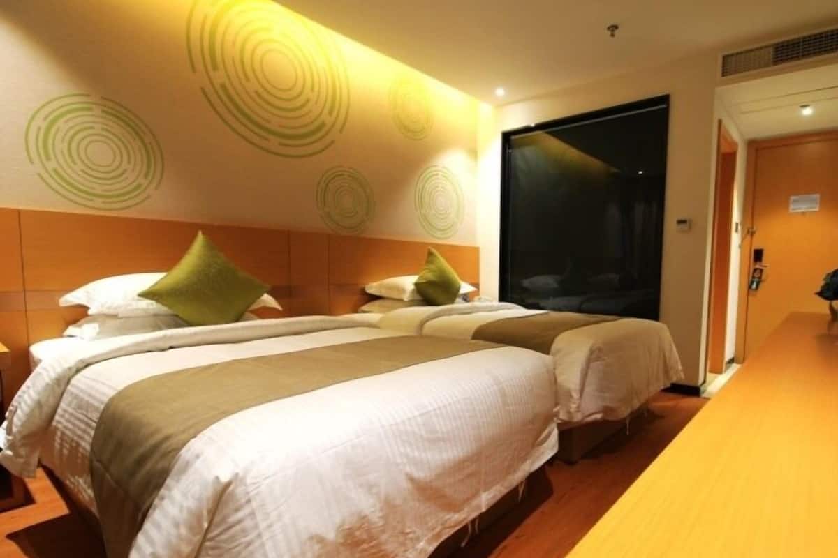 Ein Hotelzimmer mit zwei Betten, Holzboden und einem großen Fenster.