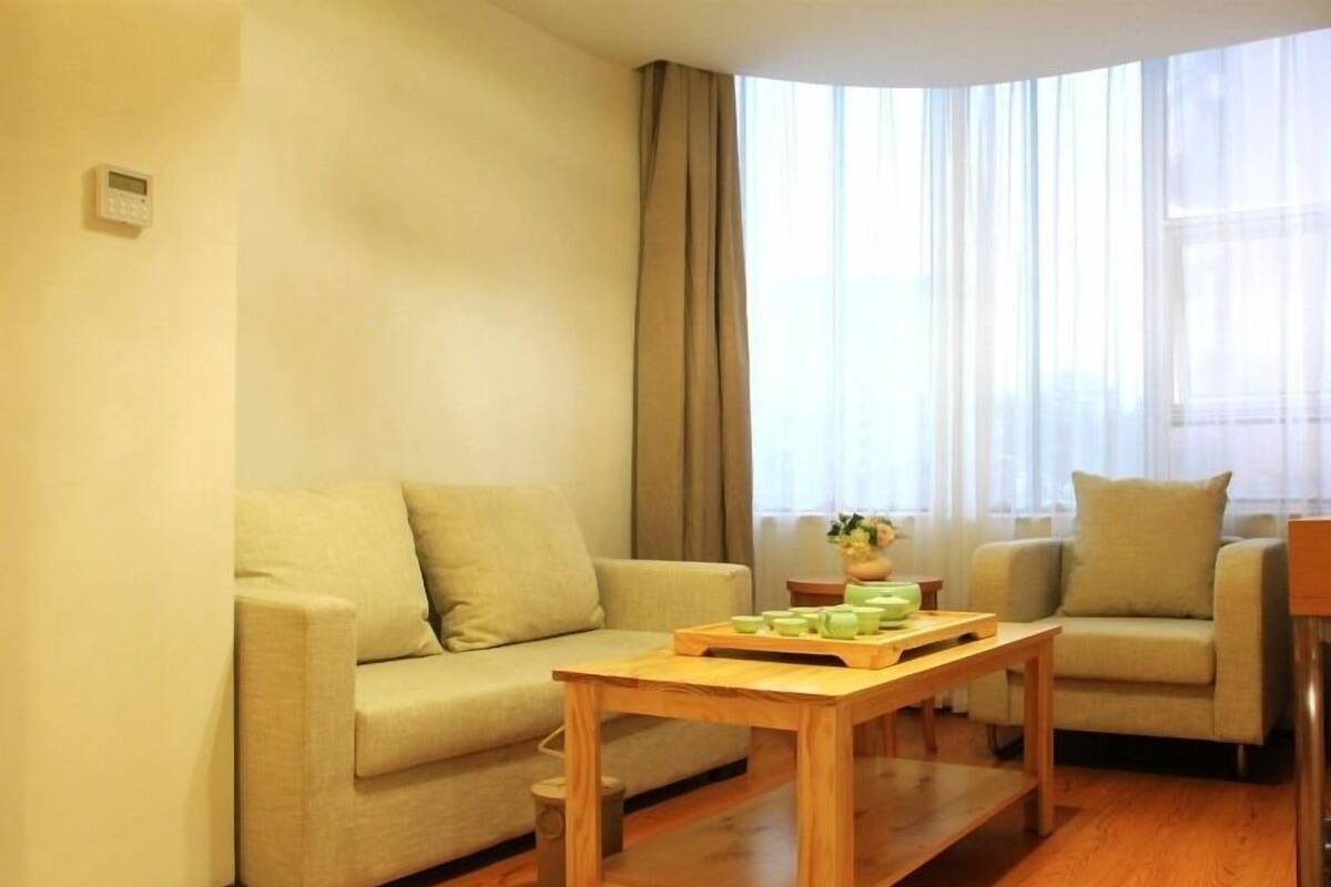 Ein modernes Wohnzimmer mit einem beigefarbenen Sofa, einem Holztisch und einem kleinen Beistelltisch mit einer Vase.