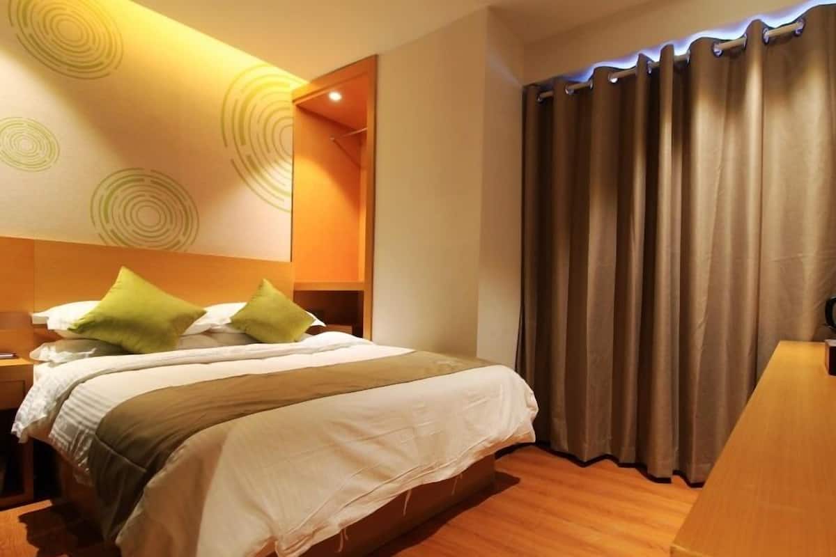 Ein Hotelzimmer mit Bett, Nachttisch, Spiegel und Vorhang.
