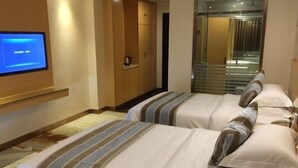 Une chambre d’hôtel avec deux lits, un téléviseur fixé au mur et une petite table.