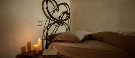 Un dormitorio con una cama, una mesita de noche con velas y un interruptor de luz en la pared.
