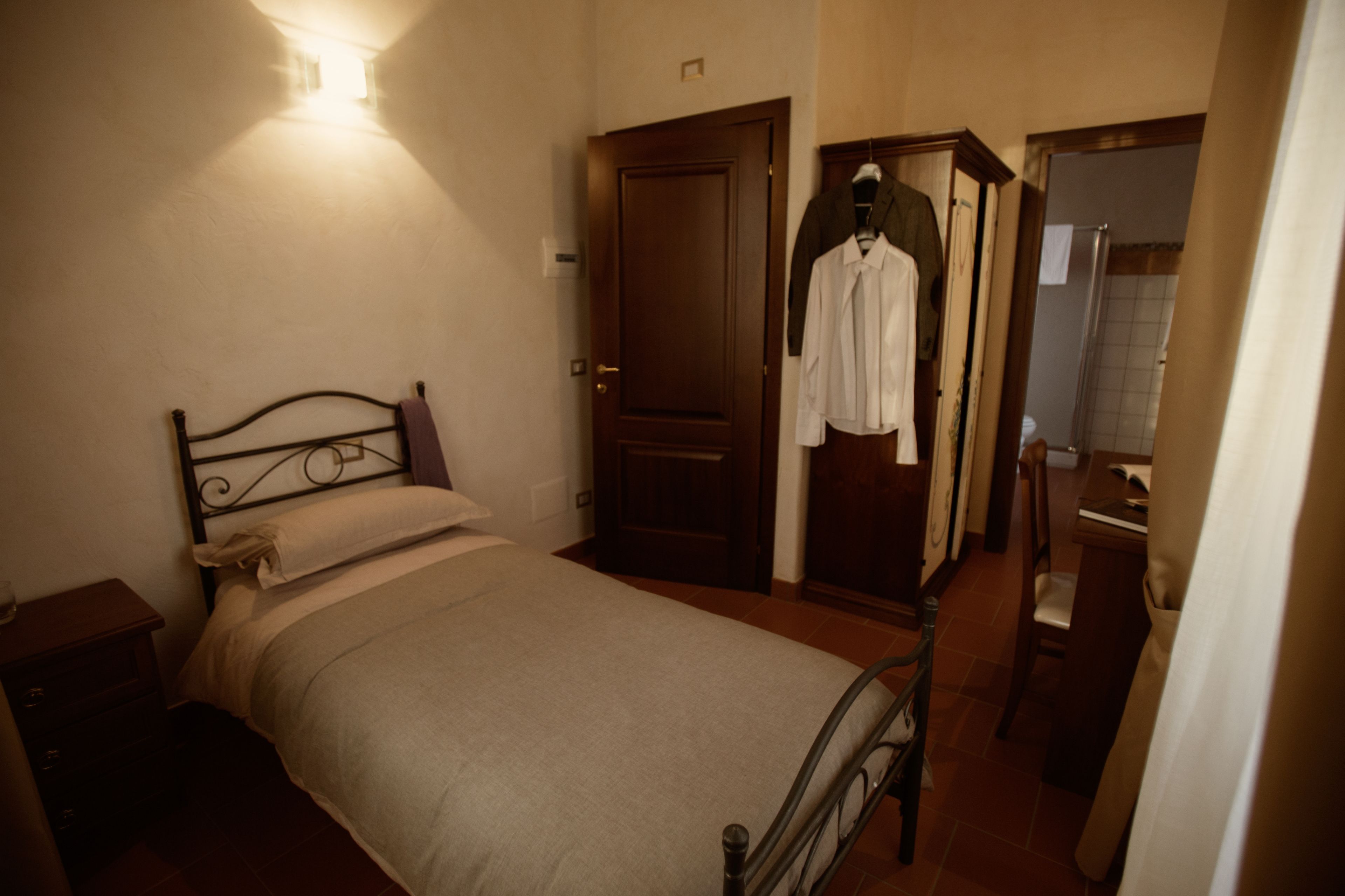 A bedroom with a bed, a wardrobe, a mirror, and a nightstand.