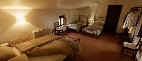 Una habitación pequeña con una cama individual, una silla y una mesita.