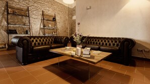 Una sala acogedora con un sofá de cuero negro, una mesa de centro de madera y una pared de piedra.