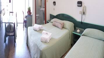 A hotel room with two beds, a desk, a chair, a telephone, and a mirror.