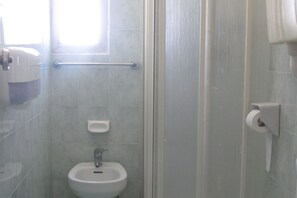 Un baño con inodoro, bidé, secador de manos y barra para toallas.