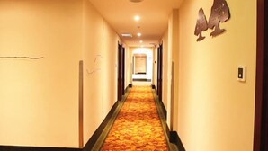 A hotel corridor with a carpeted floor and a wall-mounted decorative piece. - GreenTree Inn Tianjin Wuqing District West Yongyang Road Florentia Village Express Hotel (Tianjin)