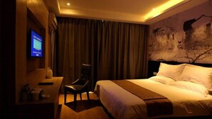 A hotel room with a bed, a desk, a chair, and a television on the wall. - GreenTree Inn Huzhou Wuxing District South Street Chaoyin Bridge Business Hotel (Huzhou)