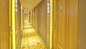 A hotel hallway with wooden doors, a carpeted floor, and overhead lighting. - GreenTree Inn Huzhou Wuxing District South Street Chaoyin Bridge Business Hotel (Huzhou)