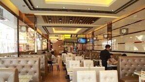 Ein Restaurant mit Sitzboxen und Tischen, Holzboden und modernem Deckenstil.