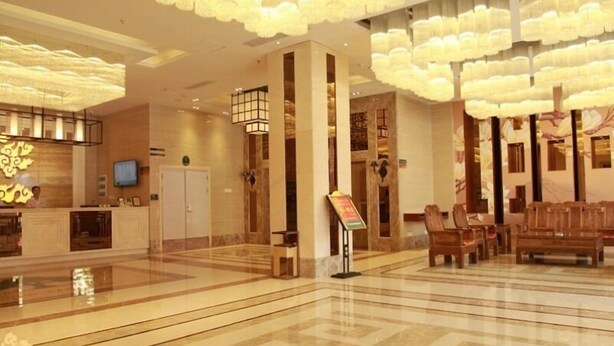 Eine Hotelhalle mit einer Rezeption, einer Sitzecke und dekorativer Beleuchtung.