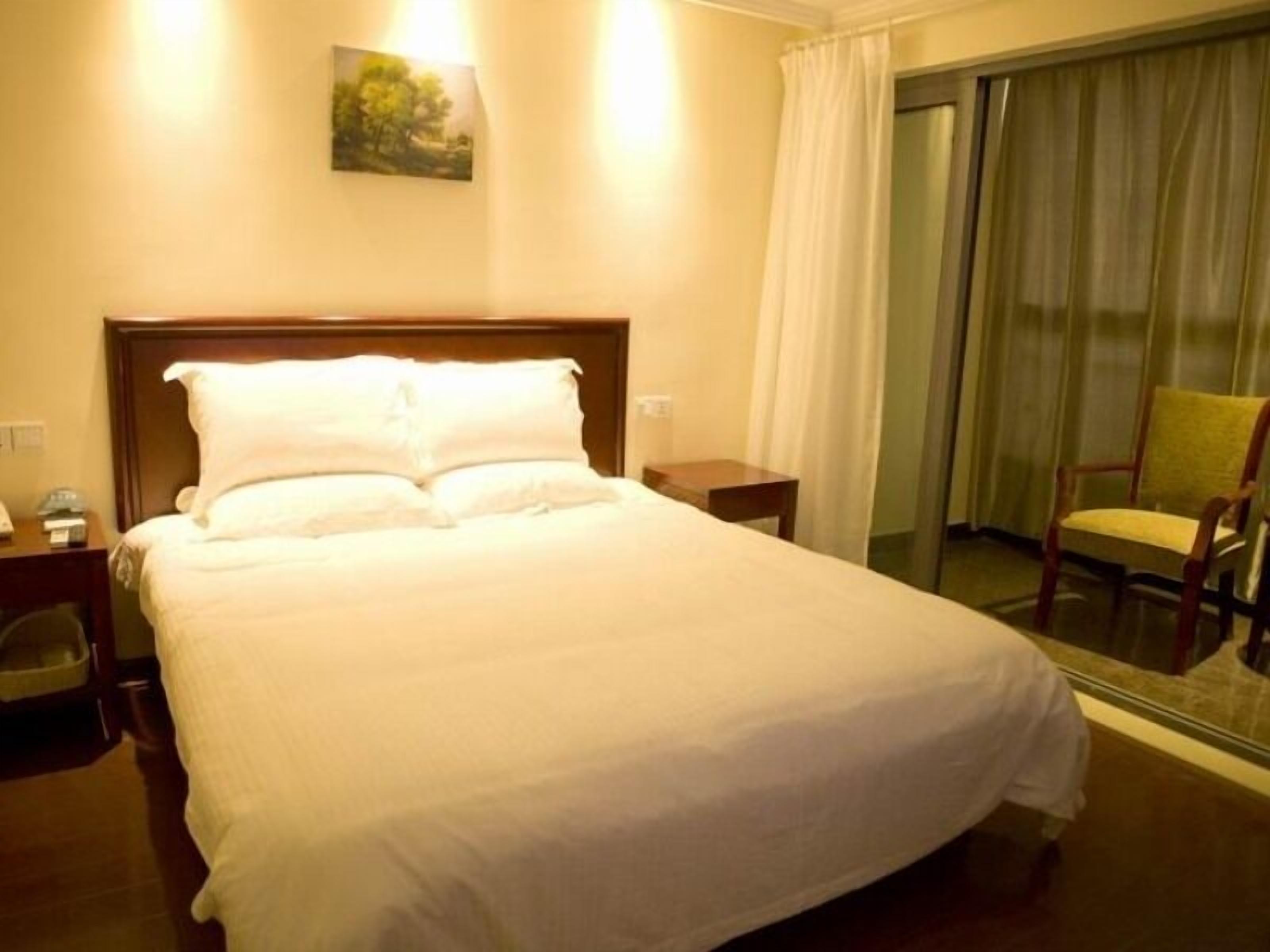 Une chambre d’hôtel avec un grand lit, une table de chevet, une chaise et une vue sur l’extérieur.