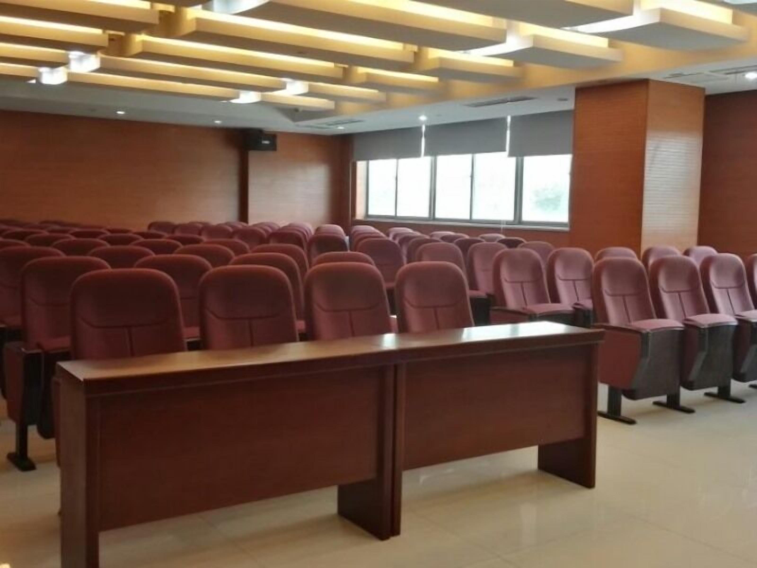A conference room with rows of chairs, a long table, and a modern ceiling design.