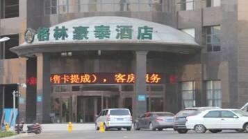 A hotel entrance with a curved facade, multiple cars parked in front, and a signboard with Chinese characters.