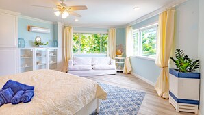 A bedroom with a bed, a ceiling fan, a window with curtains, a bedside table, and a potted plant. - Villa North Winds Orange Hill (Nassau)