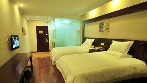 A hotel room with two beds, a desk, a television, and a door leading to another room. - GreenTree Inn Kunming Chenggong University City HSR Station Shilin Street Express Hotel (Kunming)