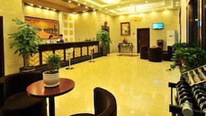 A hotel lobby with a reception desk, seating area, and a television screen. - GreenTree Inn Kunming Chenggong University City HSR Station Shilin Street Express Hotel (Kunming)