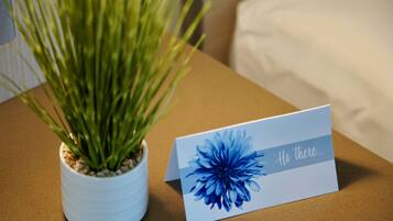 A card with a blue flower and the text "Hi there..." next to a potted plant on a table.