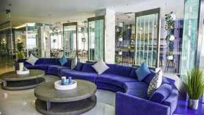 A modern lobby with a blue sectional sofa, two round coffee tables, and a glass partition.