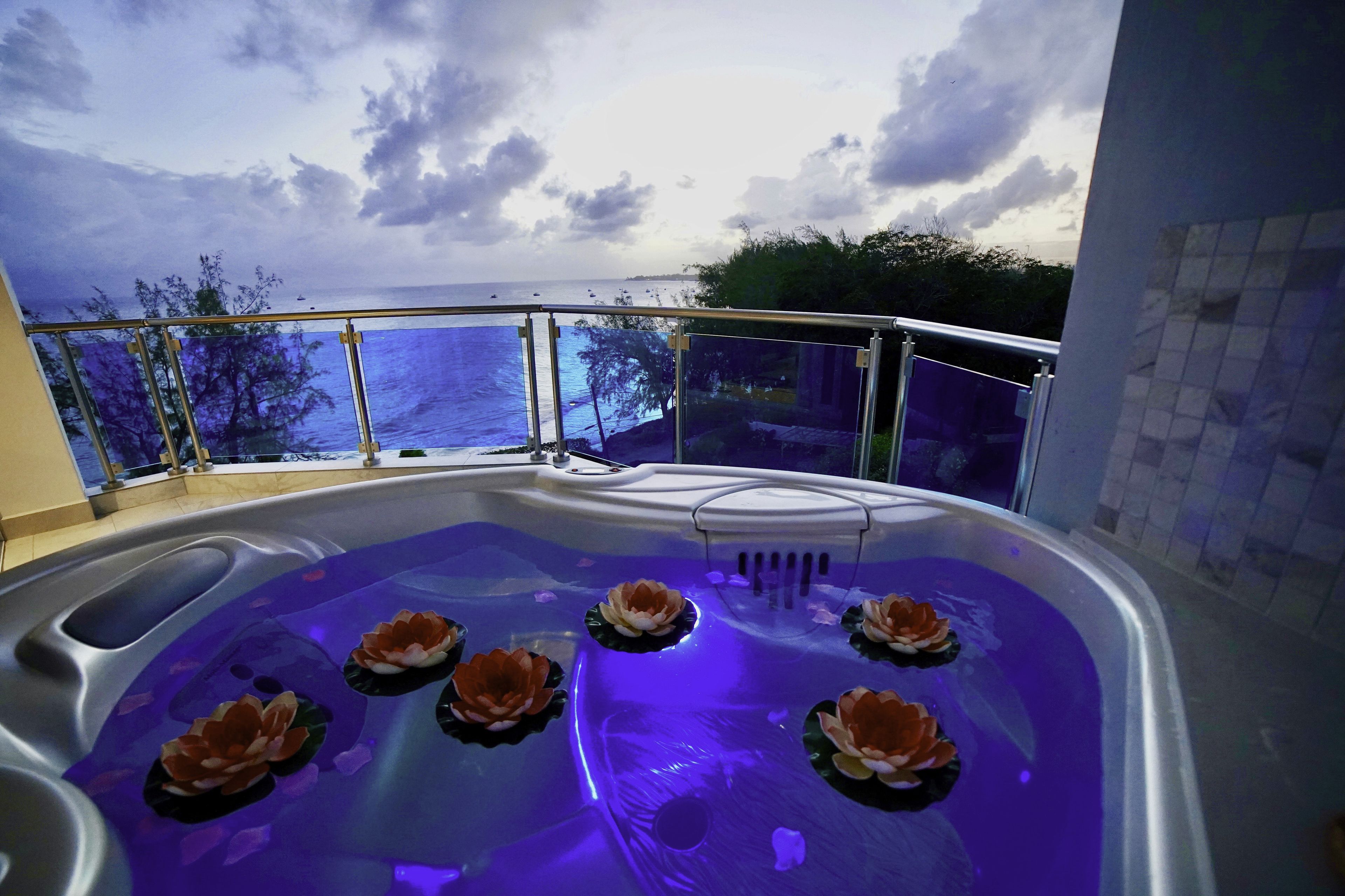 Un jacuzzi con flores de loto y vista al mar.