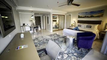 A hotel room with a bed, a desk, a chair, a TV, and a ceiling fan.
