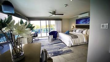 A hotel room with a bed, a desk, a chair, a large window, and a ceiling fan.