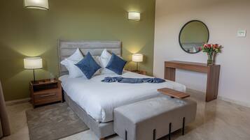 Une chambre à coucher avec un lit, des tables de chevet, des lampes, un miroir et un vase avec des fleurs.