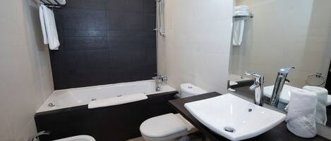 A modern bathroom with a bathtub, a bidet, a toilet, and a sink.