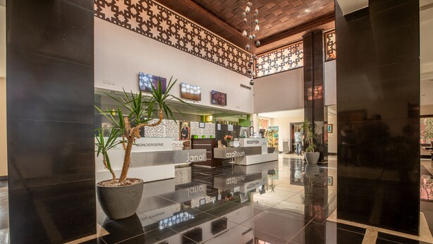 A reception area with a polished black floor, a reception desk, and a potted plant. - Condominium Hotel Resorts Oliva (Marrakech)