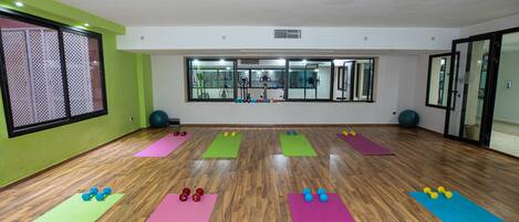 Ein geräumiger Fitnessraum mit Holzböden, Übungsmatten und verschiedenen Fitnessgeräten.