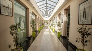 A hallway with a glass ceiling, potted plants, framed artwork, and a polished floor. - Condominium Hotel Resorts Oliva (Marrakech)