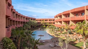 A hotel courtyard with a swimming pool, palm trees, and lounge chairs. - Condominium Hotel Resorts Oliva (Marrakech)