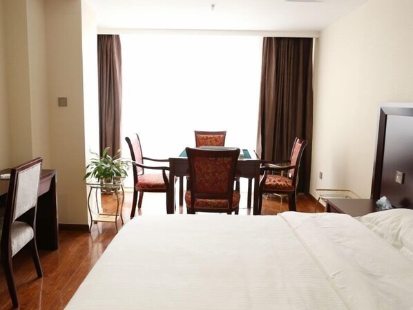 Una habitación de hotel con cama, escritorio, silla, mesa y planta en maceta.