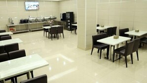 A spacious cafeteria with multiple tables and chairs, a television screen on the wall, and a counter with various items. - GreenTree Inn Changzhou Henlin Town Zhongtian Express Hotel (Changzhou)
